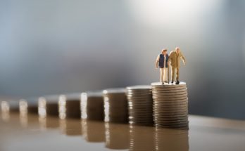 Figures of an elderly couple climbing a stack of coins