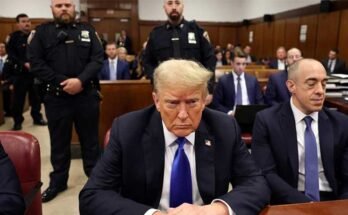 Donald Trump sitting at a table in a court room